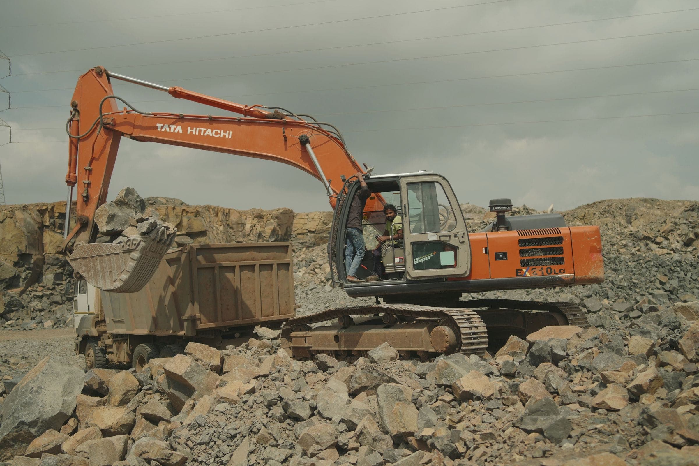 An excavator loading rock into a dump truck at a quarry